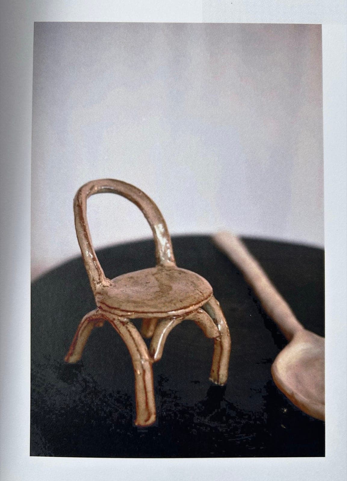 A tiny ceramic chair beside a ceramic spoon