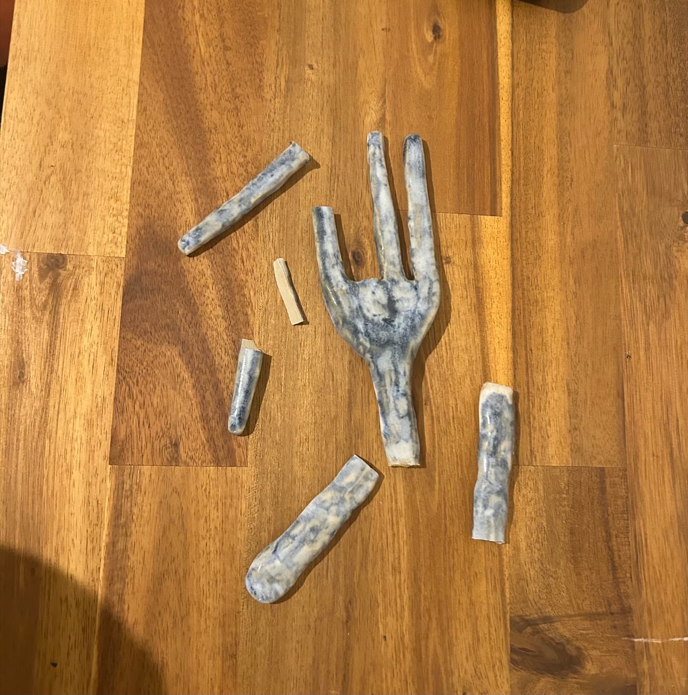 A ceramic fork broken into several pieces on a wooden table